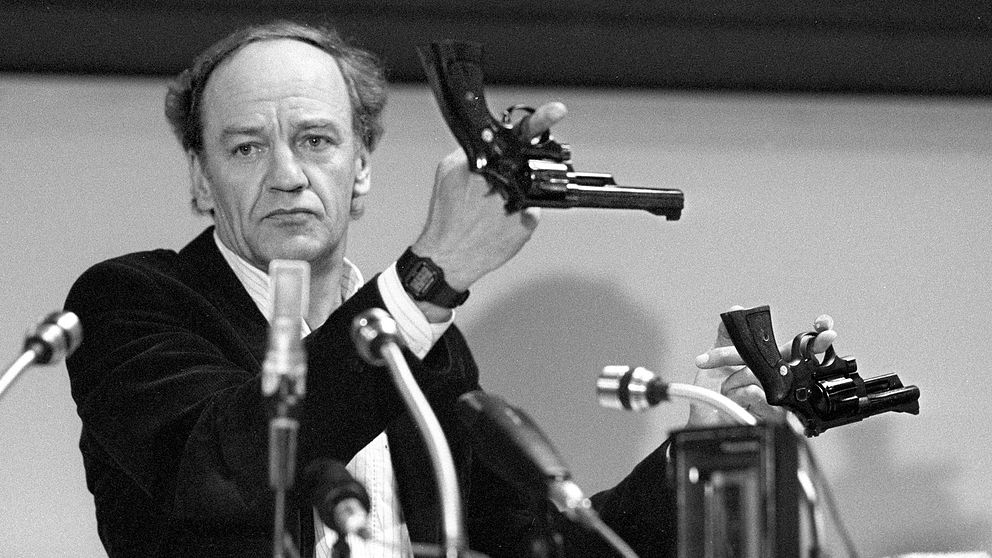 Länspolismästare Hans Holmér håller upp två revolvrar av märket Smith & Wesson 357 Magnum under en presskonferens på polishuset i Stockholm 31:a mars 1986. Detta slags vapen tros vara den typ av vapen som kan ha använts vid mordet på Sveriges statsminister Olof Palme.