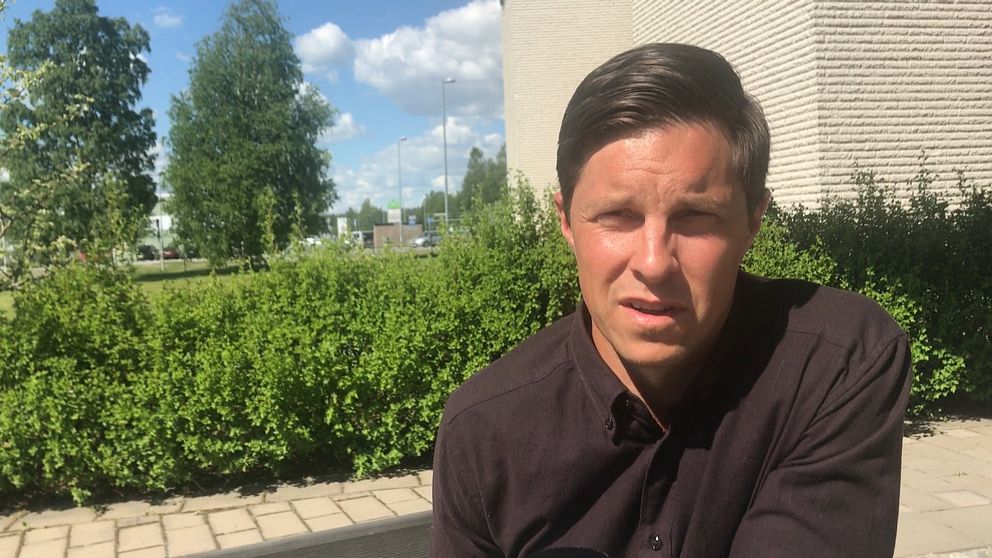 Regionschef för Företagarna i Västerbotten Jonas Nordin i svart skjorta intervjuad utomhus med buskar och husvägg i bakgrunden.