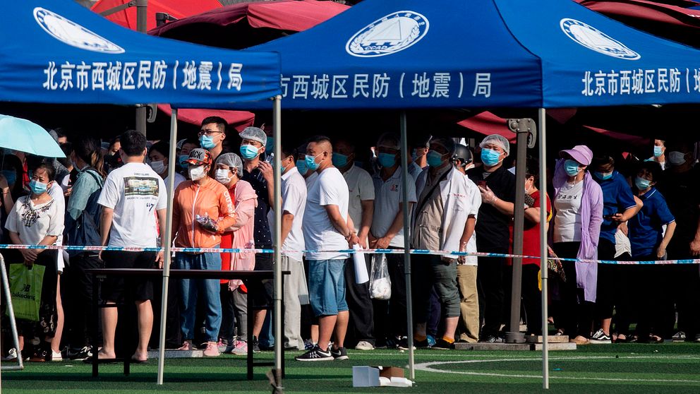 Skolor stängs och reserestriktioner införs i Peking, efter att ett nytt utbrott av coronaviruset har upptäckts i staden. Bilden visar människor i Peking som står i kö för att få testa sig för viruset.