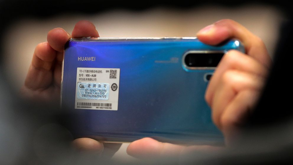 En person håller upp en blå Huawei-mobil.