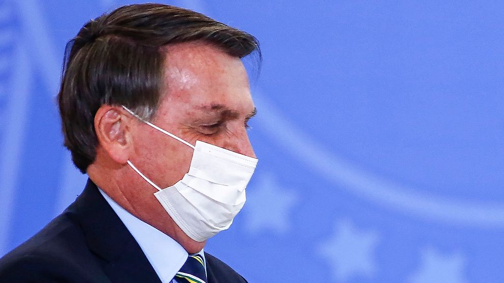 Närbild på Brasiliens president Bolsonaro i profil, iförd ansiktsmask under en formell tillställning.