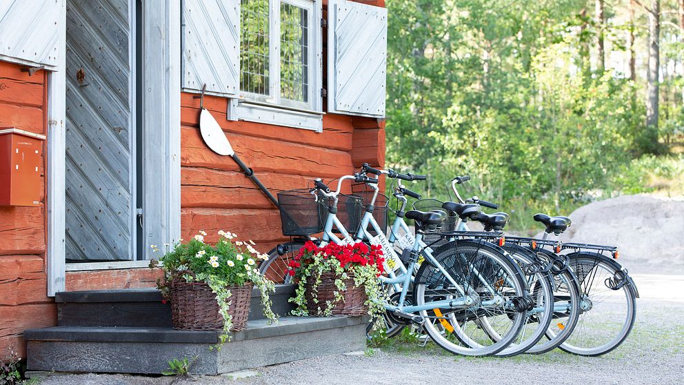 cyklar parkerade utanför gammeldags trähus med kajakpaddel på väggen