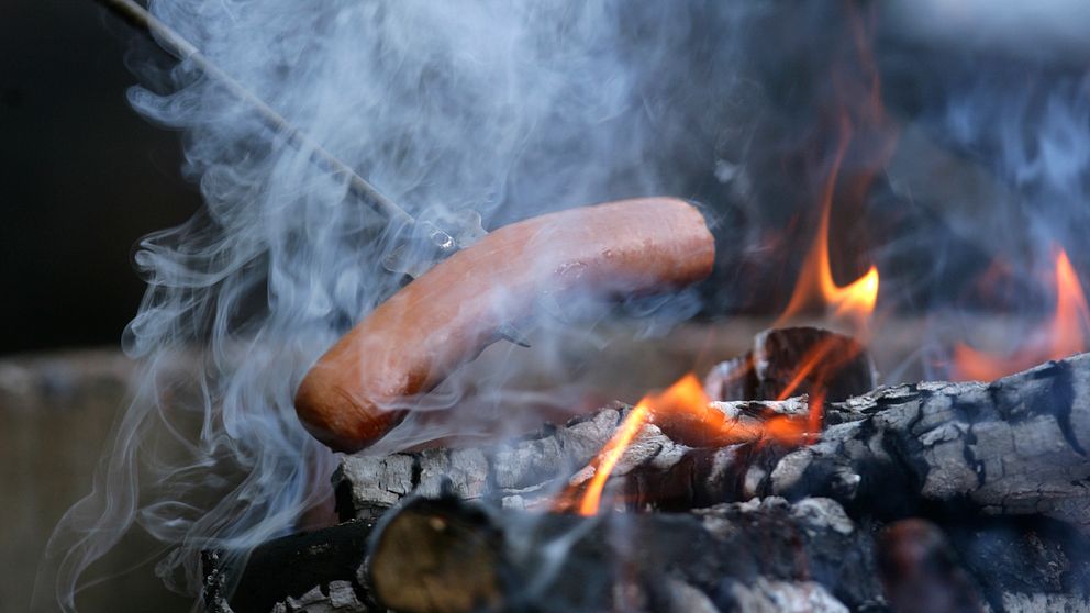 En korv som grillas utomhus över en öppen eld.