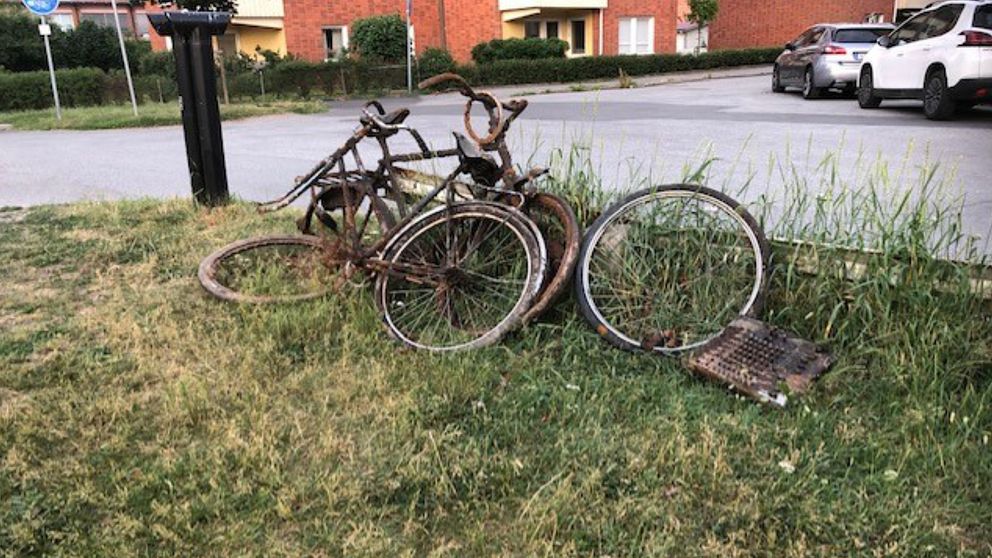 Rostiga cyklar står lutade mot ett räcke.