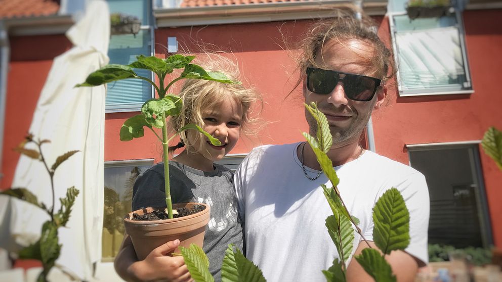 Gunnar Bange står framför sitt hus med sin dotter i famnen