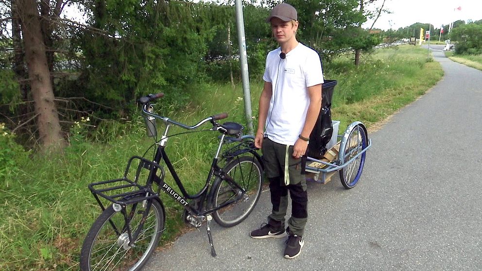 Johan Eriksson står på en cykelväg framför sin cykel och kärra.