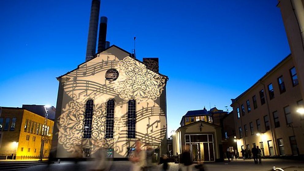 Värmekyrkan i Norrköping under Kulturnatten med ljusspel av ornament och noter.