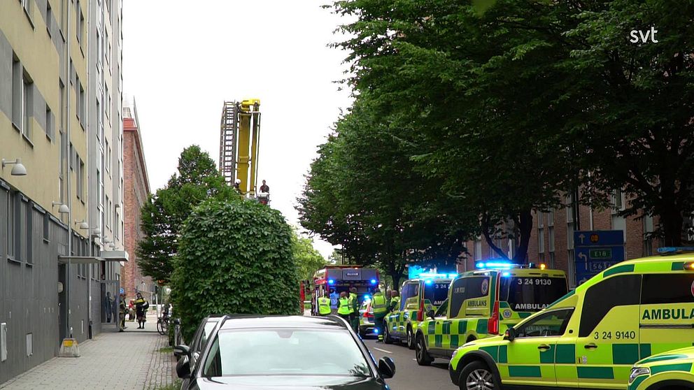 Tre ambulanser och en brandbil på gatan utanför en fastighet.