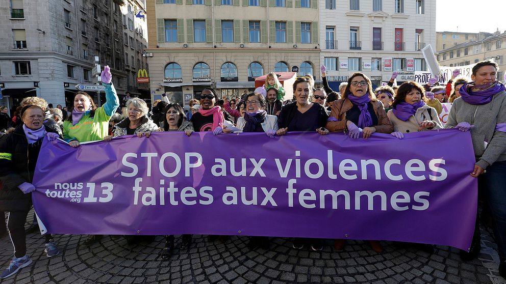 Feministiska demonstranter med en lila banderoll.
