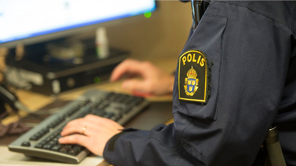 En polis arbetat vid en dator.