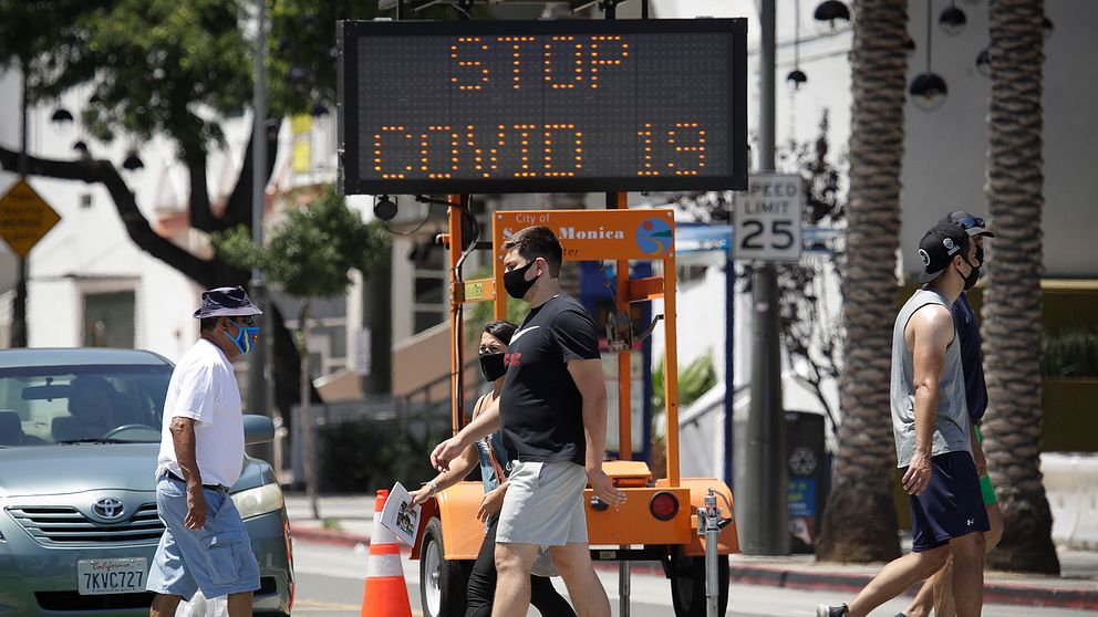 Santa Monica, Kalifornien. Fotgängare med munskydd korsar ett övergångsställe.