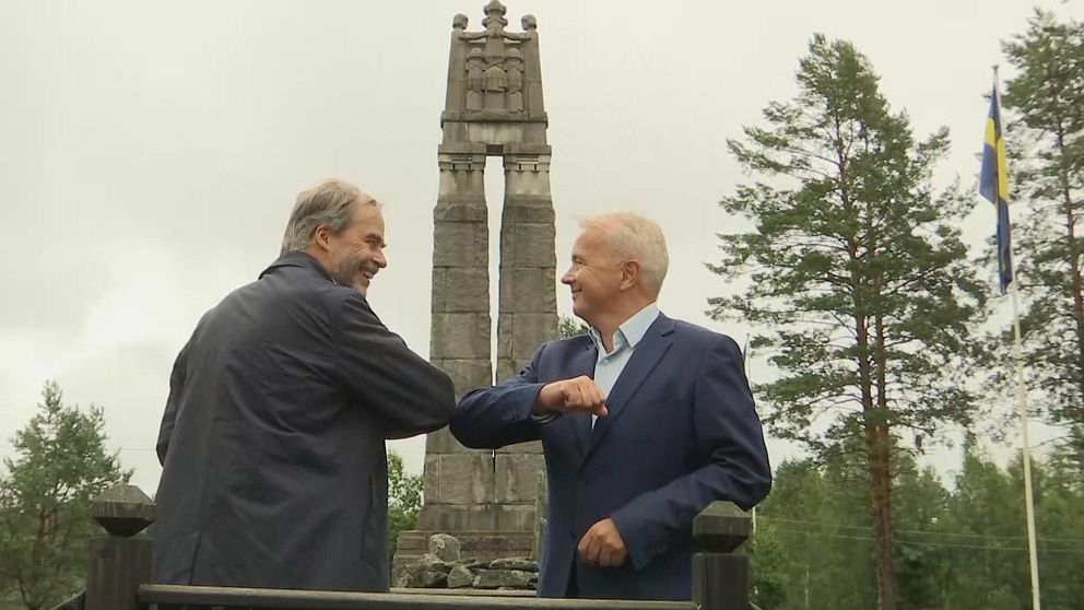 Georg Andrén och Knut Storberget gör en coronahälsning med armbågarna framför fredsmonumentet i Morokulien.