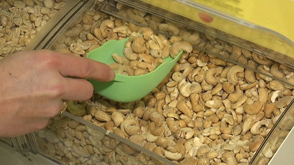 nräbild en hand som tar cashew-nötter ur lösviktslåda med en skopa