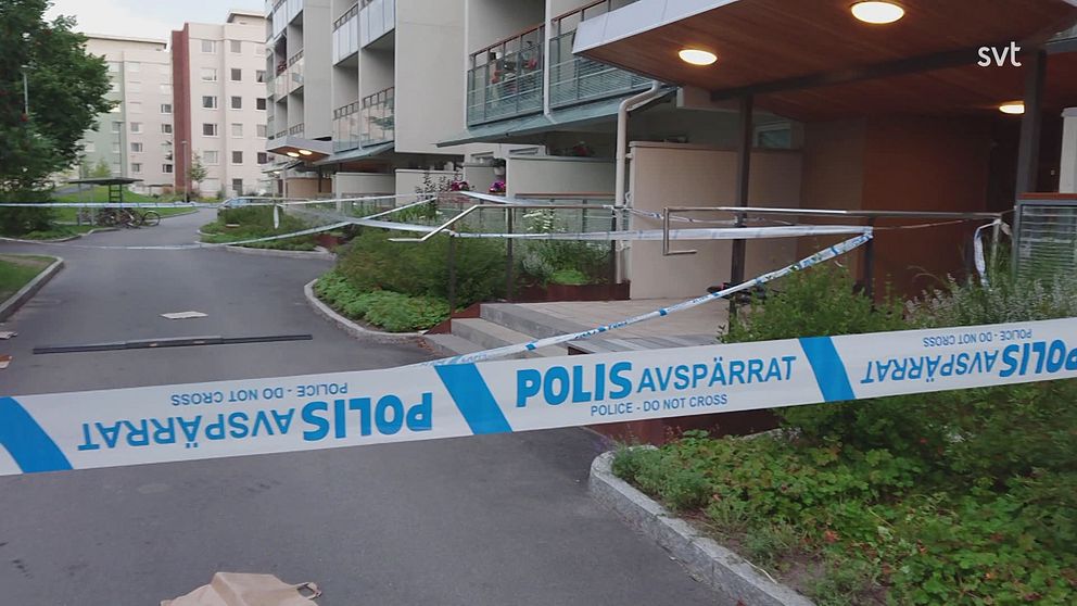 Bostadsområde i bakgrunden med av polisen uppsatt avspärrningstejp i förgrunden.