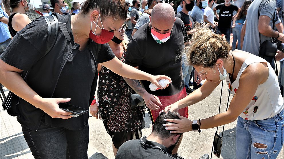 Demonstranter hjälper en annan med en huvudskada.