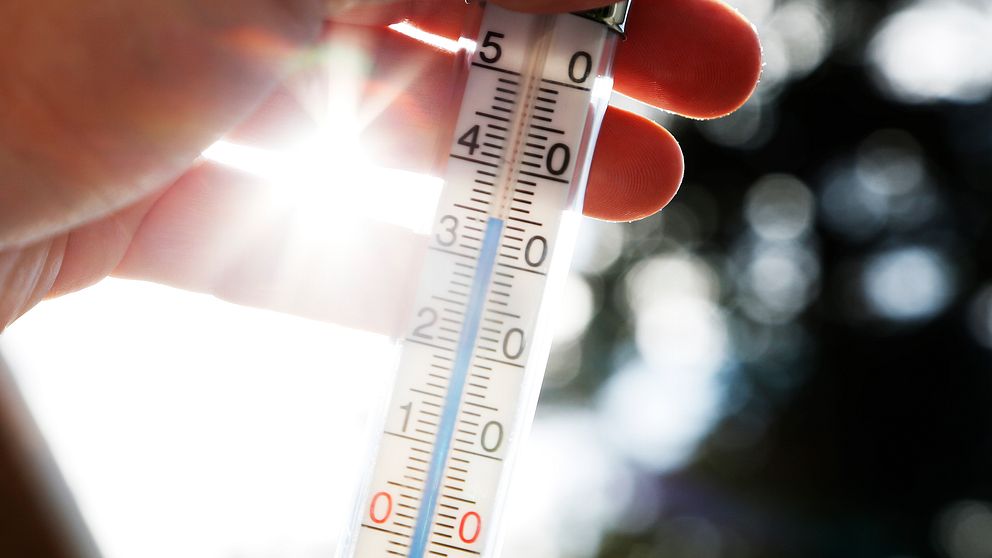 En hand håller i en termometer som visar 35 plusgrader.