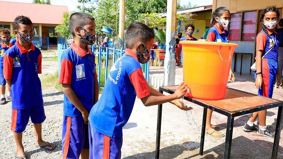 Elever i en grundskola i Dili i Östtimor som tvättar händerna när deras skola öppnar efter att ha varit stängd under corona-pandemin.