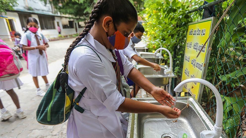 Elever i Sri Lankas huvustad Colombo som tvättar händerna när skolan ska öppna efter att ha varit stängd på grund av covid-19.