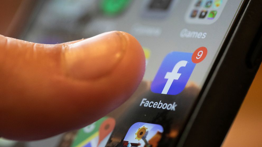 Tumme som trycker på Facebook-applikationen på en smartphone.