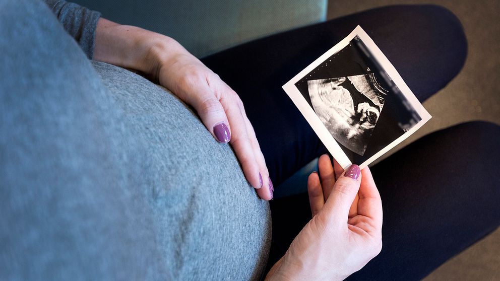 Genrebild. En gravid kvinna håller i ett ultraljudsfoto.