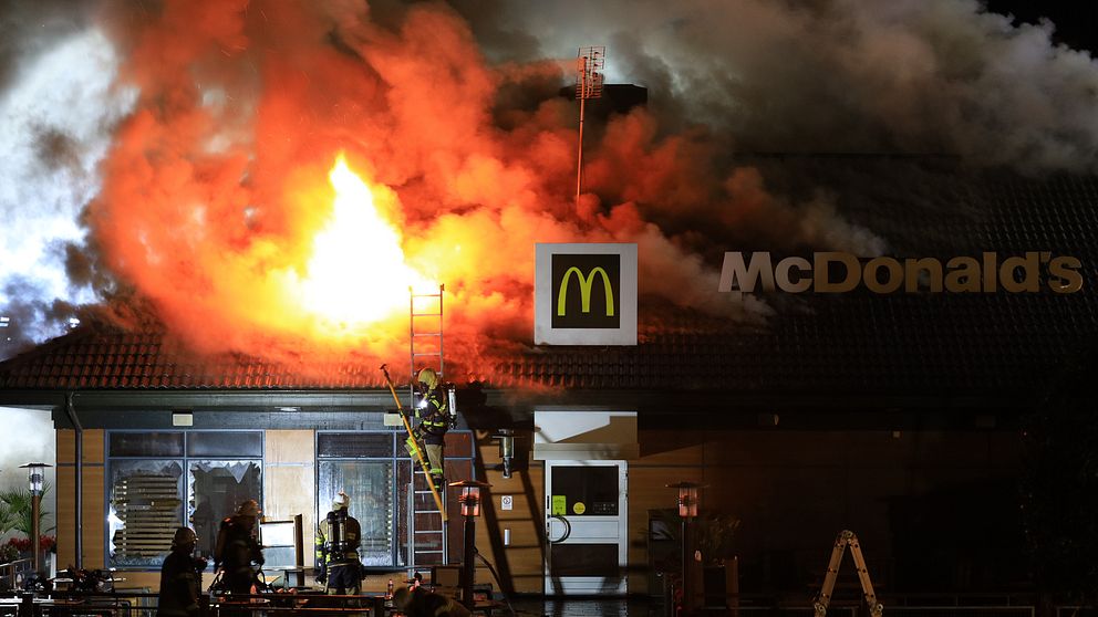 Brandmän bekämpar brand på McDonalds-restaurang. Eld slår upp genom taket.