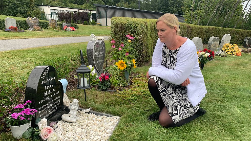 Carola Jakobsson sitter på huk vid en svart gravsten på kyrkogården i Kil.