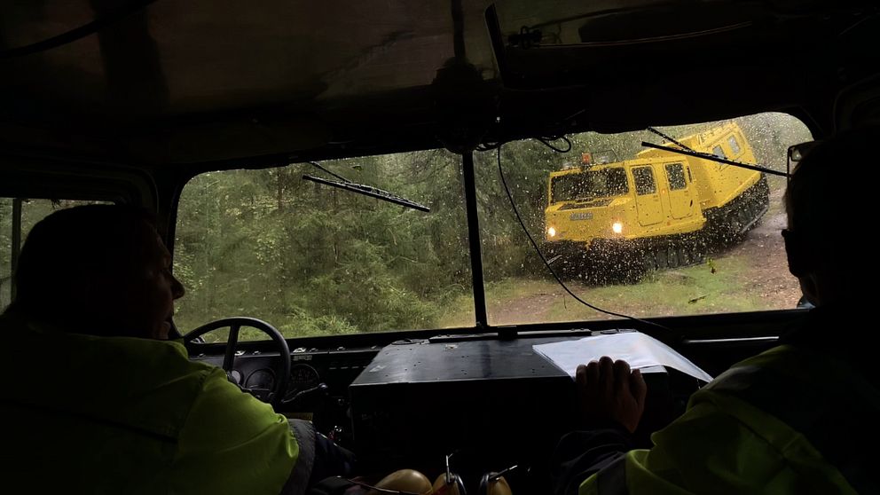 Sikt ut från en bandvagn som möter en likadan gul bandvagn på en skogsstid.