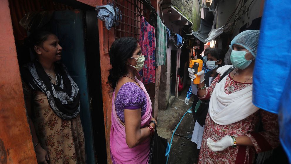 Sjukvårdspersonal screenar invånare i slumområdet Dharavi i Bombay, ett av de största slumområdena i Asien.