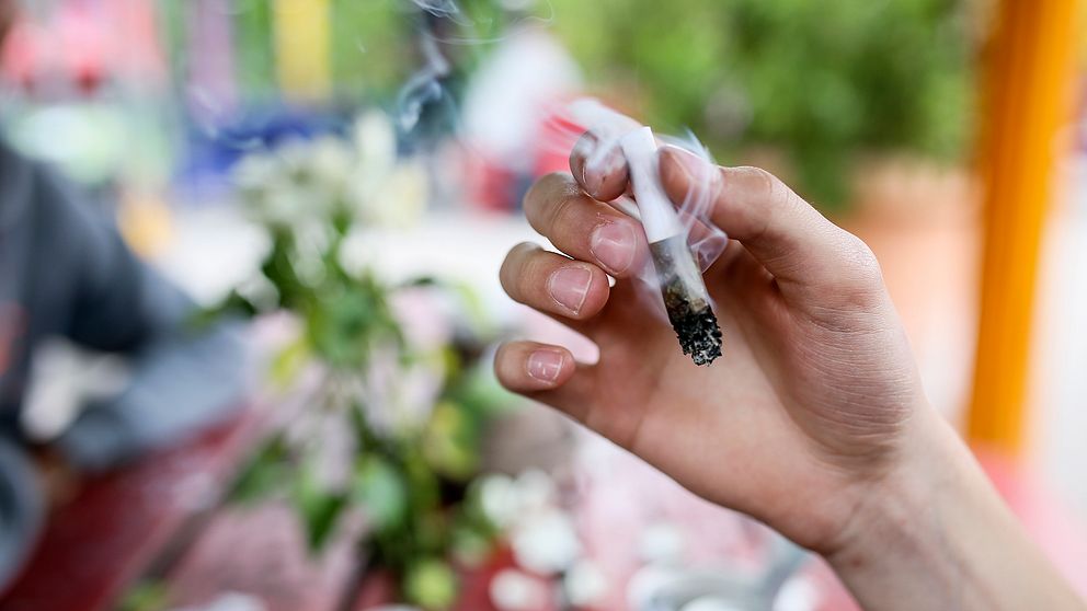 Bilden visar en hand med en cannabis-joint