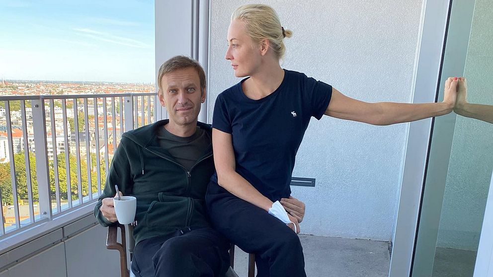 Aleksej Navalnyj med en kaffekopp i handen tillsammans med frun Yulia på en balkong.