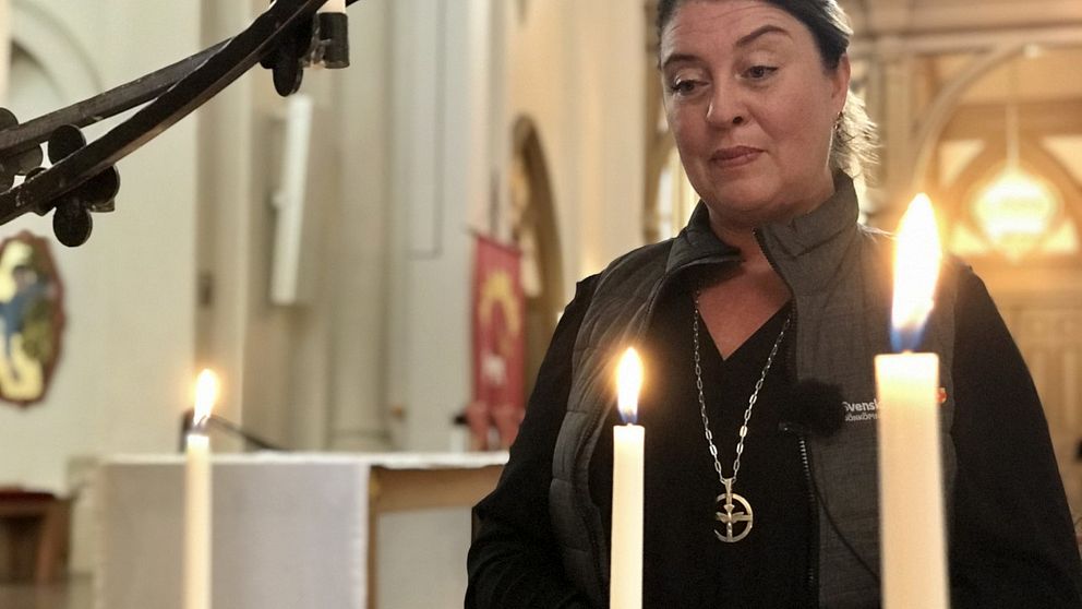 Linda Wennerholm, diakon i Svenska kyrkan i Jönköping står i en kyrka med levande ljus i förgrunden.