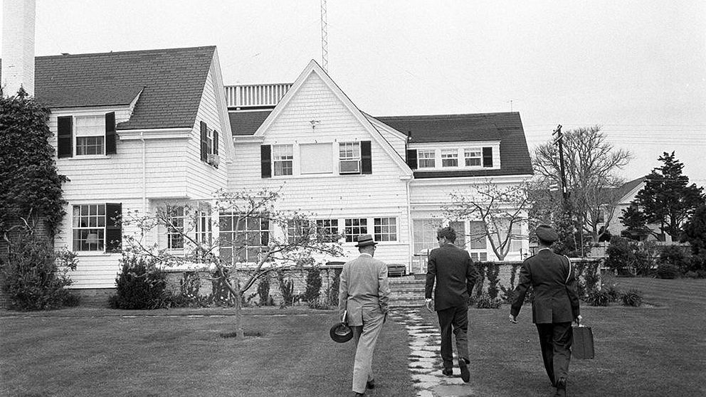 President John Kennedy (mitten) och medhjälparen general Chester Clifton (höger) med portföljen ”kärnvapenfotbollen” i Hyannis Port den 10 maj 1963.