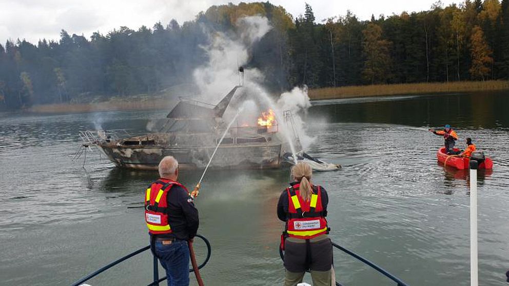 Brinnande båt släcks med vatten.