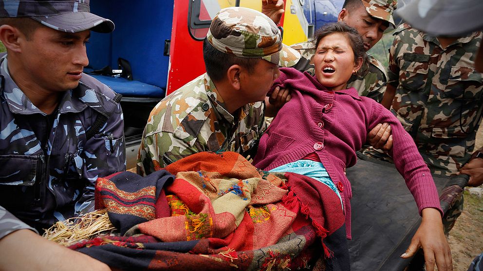 Sita Karka, som brutit båda benen när rasmassor fallit över henne, bärs till räddningshelikopter i Gorkha, Nepal.