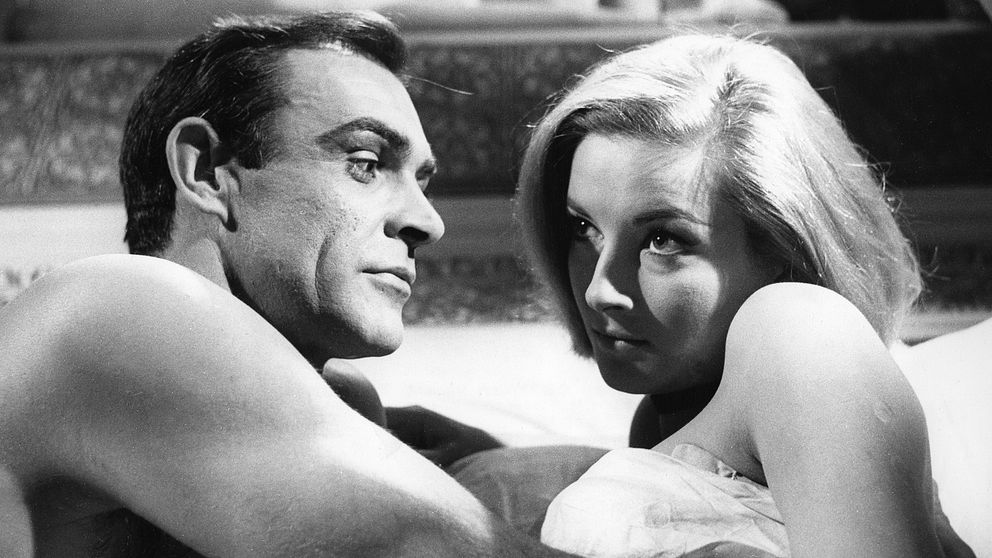 Svartvit bild där Sean Connery och skådespelerskan Daniela Bianchi ligger i bara överkroppar under ett täcke.