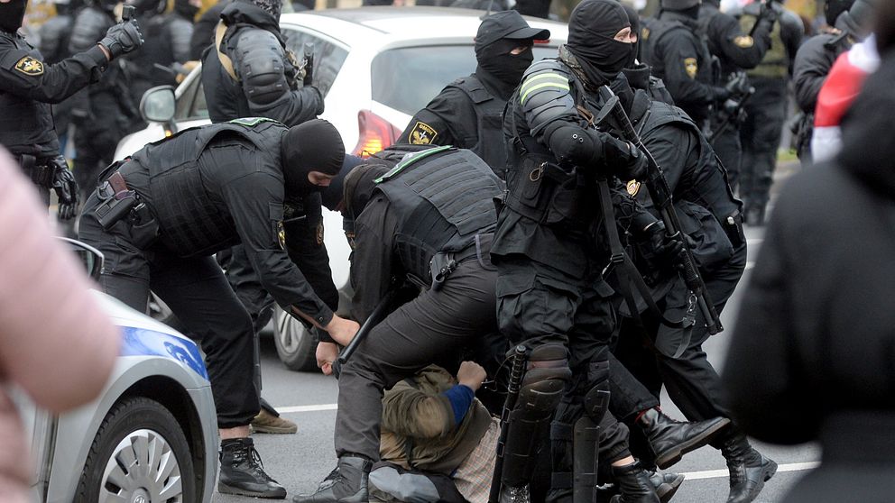 Poliser griper en demonstrant under söndagens protester i Minsk.