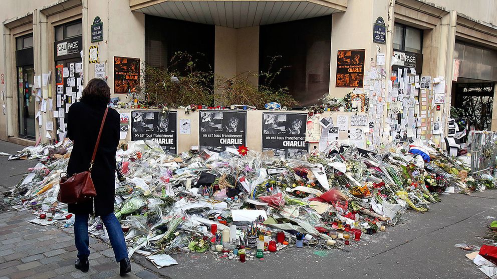 Blomsterberg utanför satirtidningen Charlie Hebdos redaktion i Paris där nio journalister sköts till döds i januari.