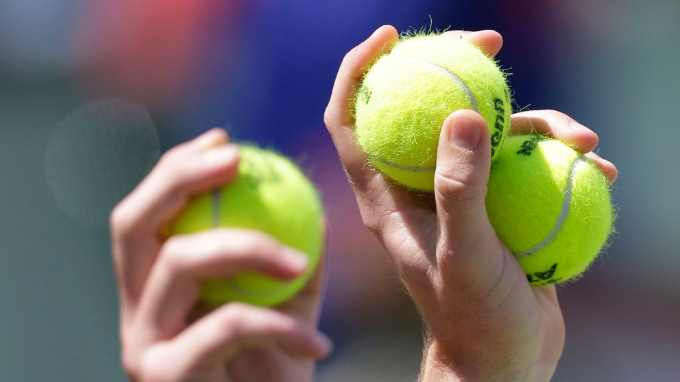 Två händer som  båda håller i tennisbollar.