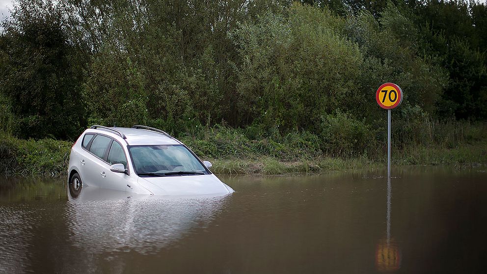 En bil halvvägs täckt av vattenmassor i Getinge, Halland förra sommaren.