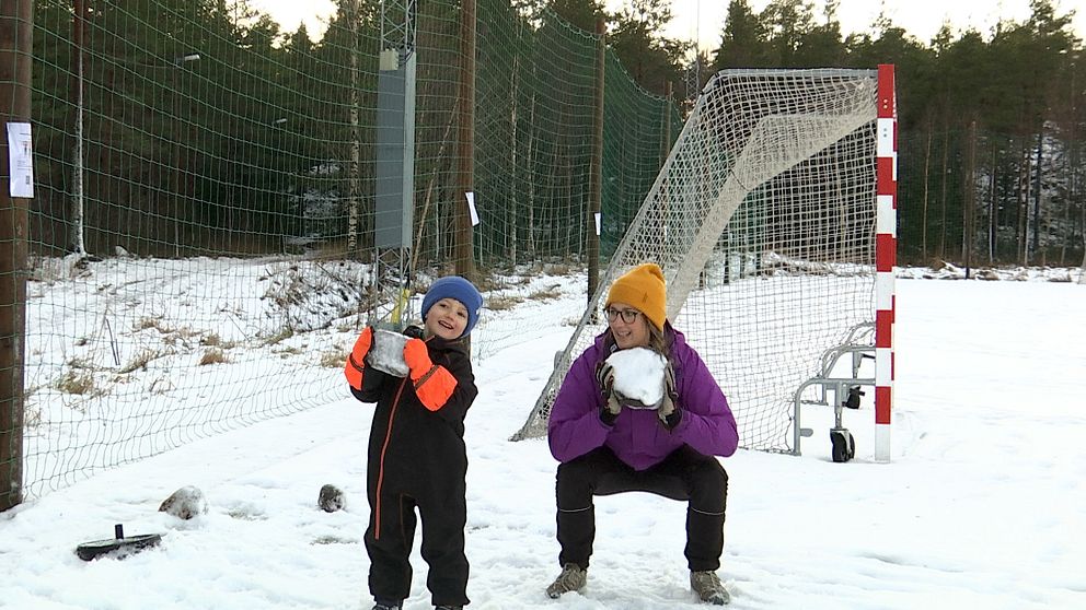 Tjej och hennes son på en snöig fotbollsplan