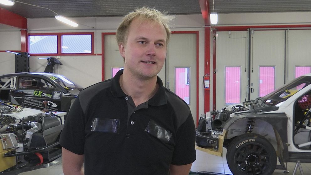Joel Christoffersson i sitt garage med rallycrossbilar i bakgrunden.
