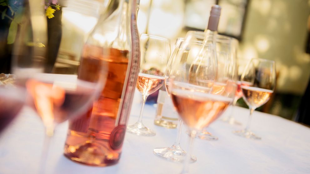 Bilden visar flaskor med rosévin och vinglas på ett bord med vit duk.