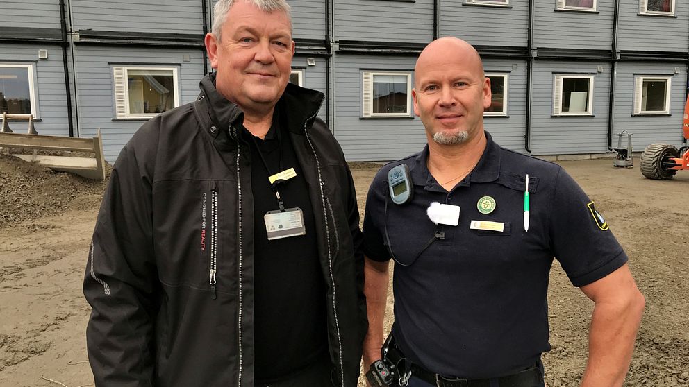 Tomas Kvarnrud, kriminalvårdsinspektör, och Thomas Gustafsson, skyddsombud, framför grå baracker i två våningar