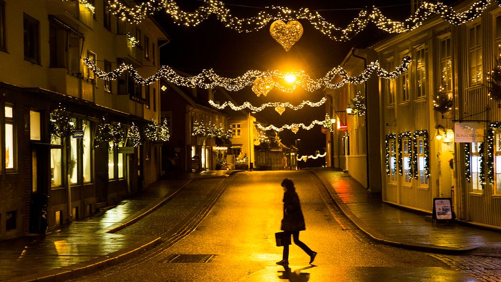 Ensam person på gata med julbelysning.