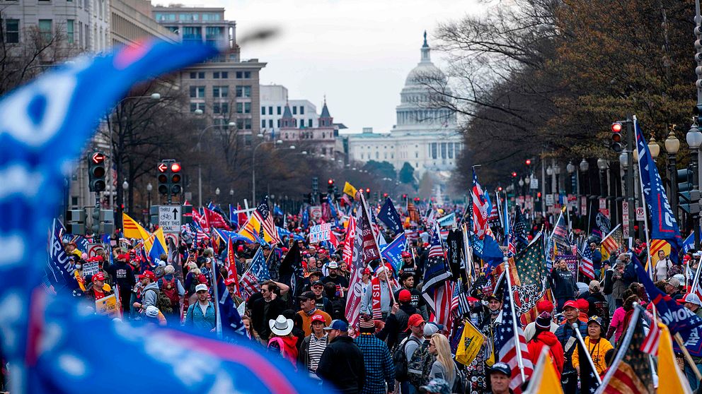 En stor skara Trumpsupportrar marcherar på en stor gata i Washington D.C.