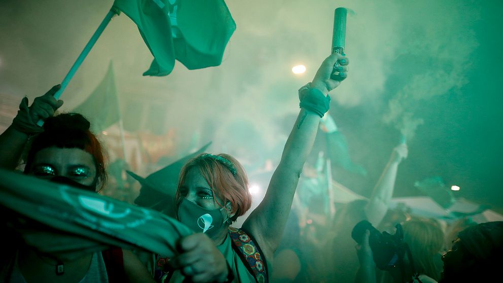 Kvinnliga aborträttsaktivister med munskydd firar på Buenos Aires gator.