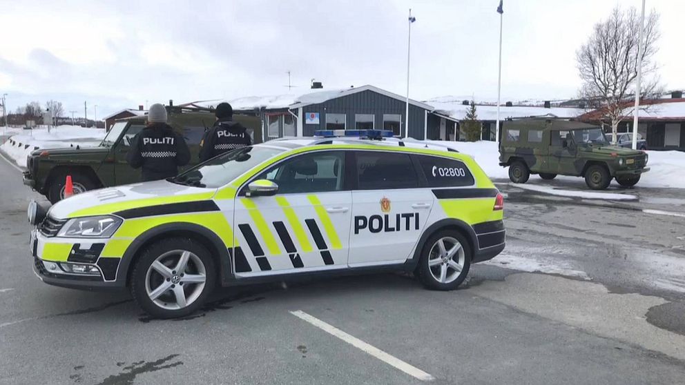 Bild på norsk polisbil på en väg. Två poliser står vid bilen.