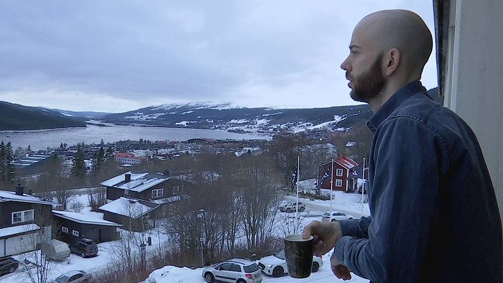 en man på balkong blickar ut över Åre by och Åresjön