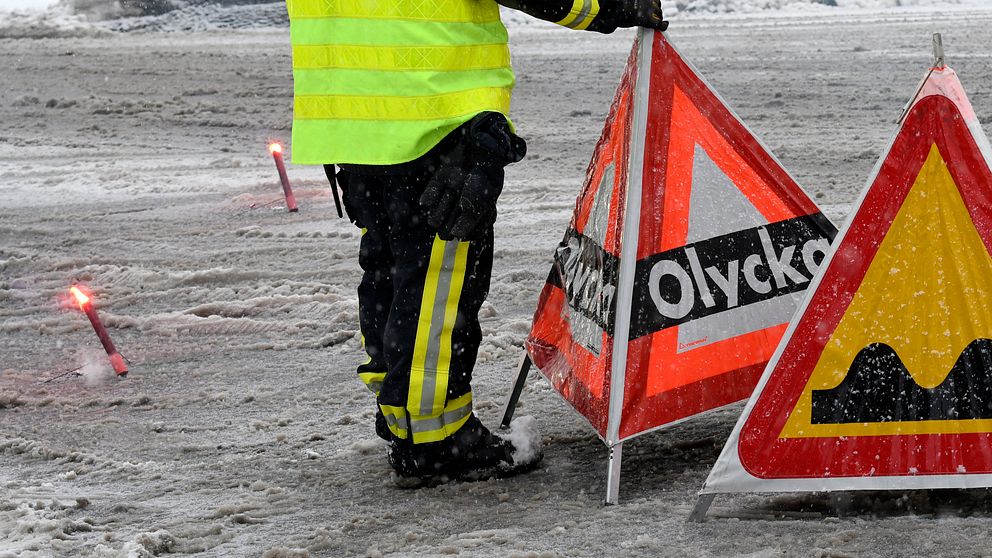 Bilden visar när personal från räddningstjänsten varnar med skylt om en olycka på vägen.