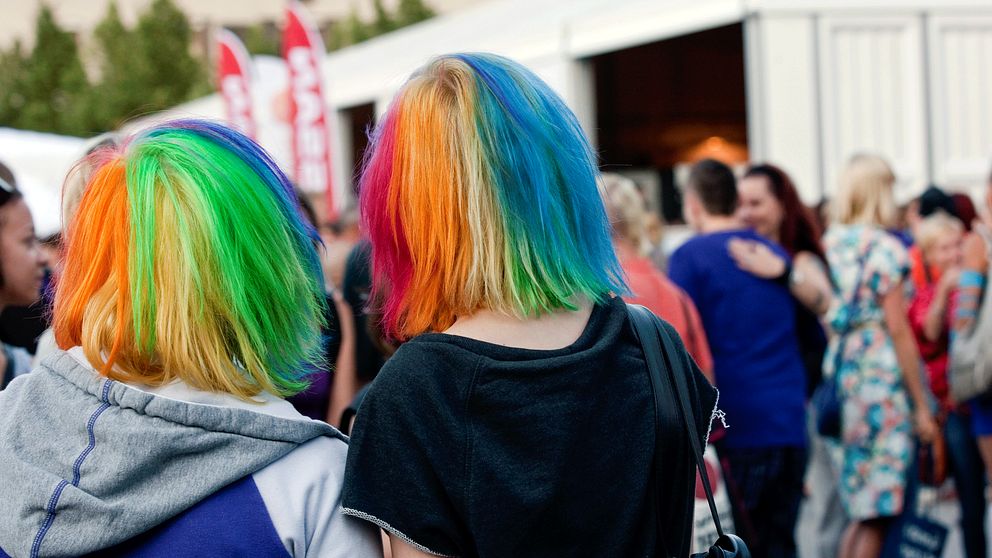 Två personer som färgat sitt hår i regnbågsfärger.